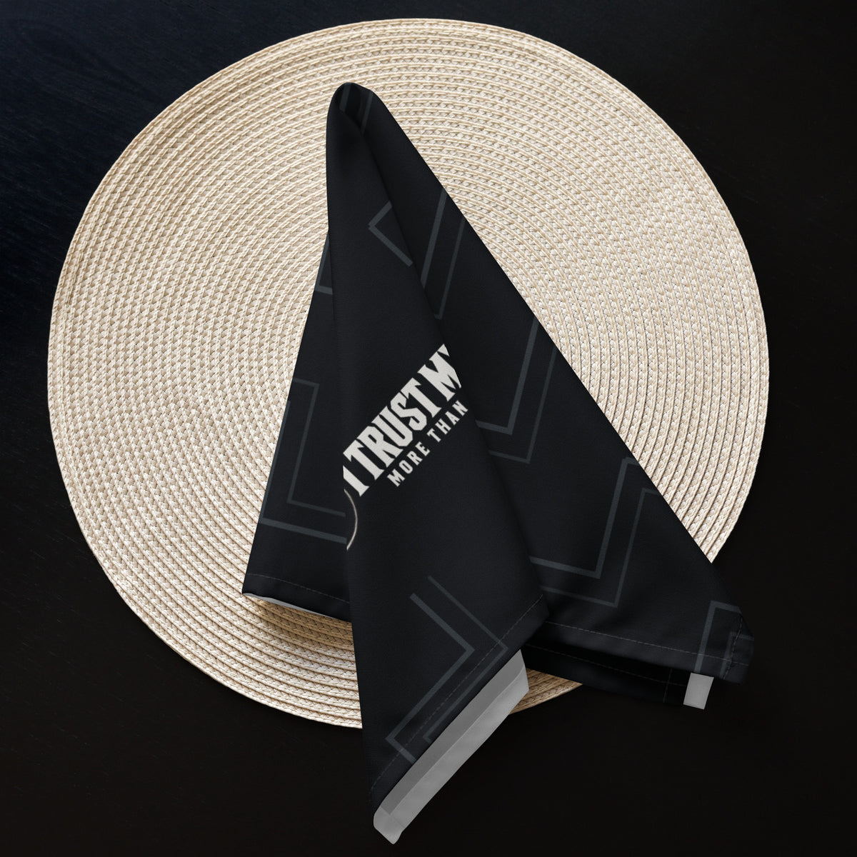 A black Quiet Company I Trust My Pet™ napkin folded on a round plate in a dining table setting.