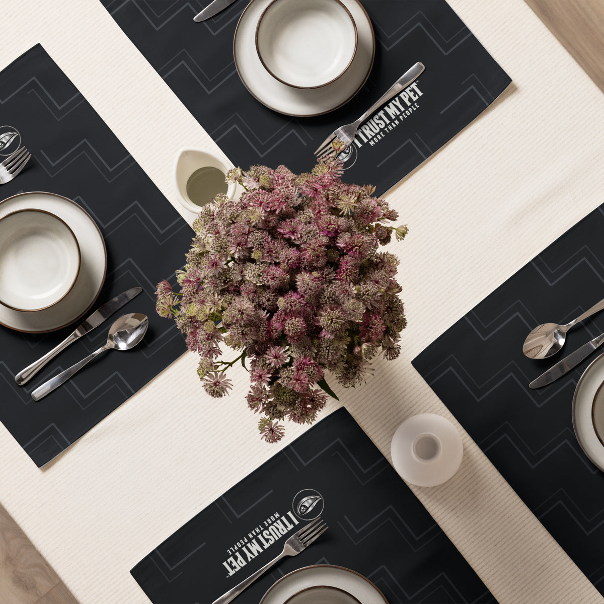 Quiet Company black I Trust My Pet™ placemats arranged on a dining table with plates and a floral centerpiece.